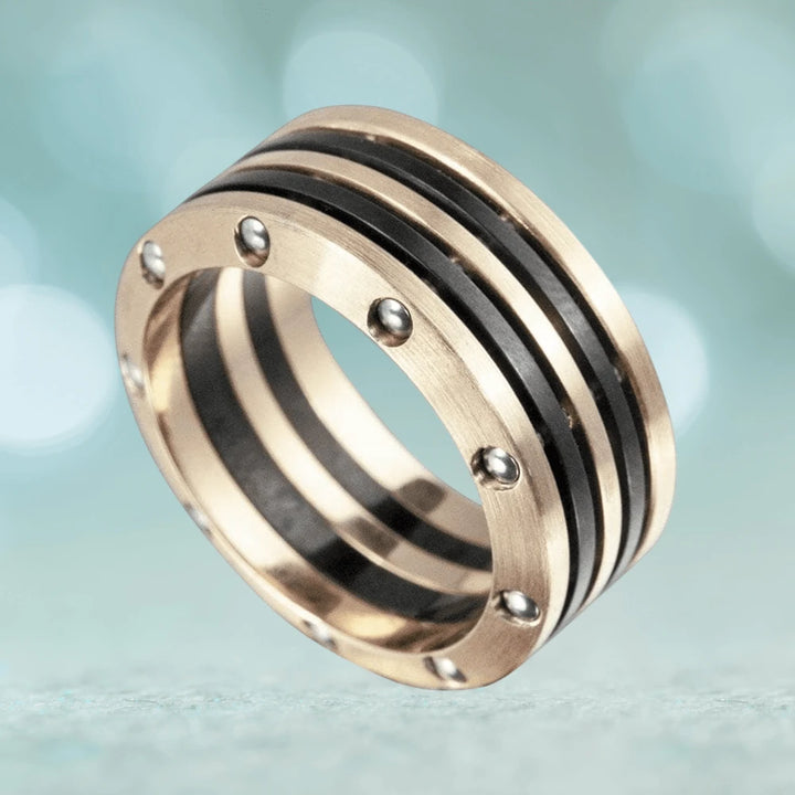 Men's Evolution Ring in stainless steel with two-tone plating, featuring bold black stripes and metallic rivet accents for a modern masculine jewelry statement.