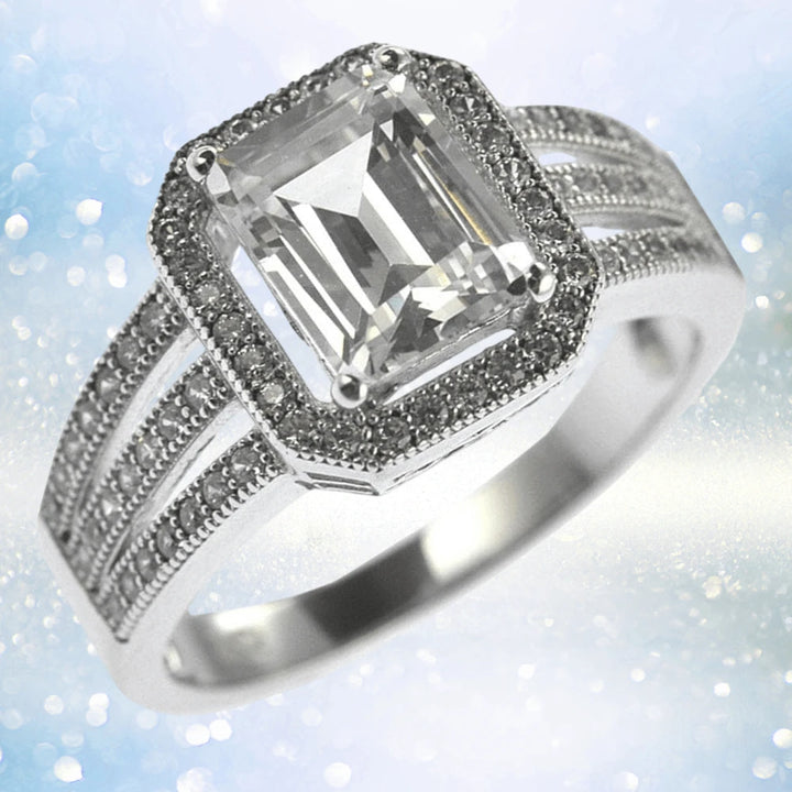 Artica Ring featuring a sterling silver band with rhodium plating, showcasing a large emerald-cut clear gemstone surrounded by smaller stones, designed for women’s jewelry.
