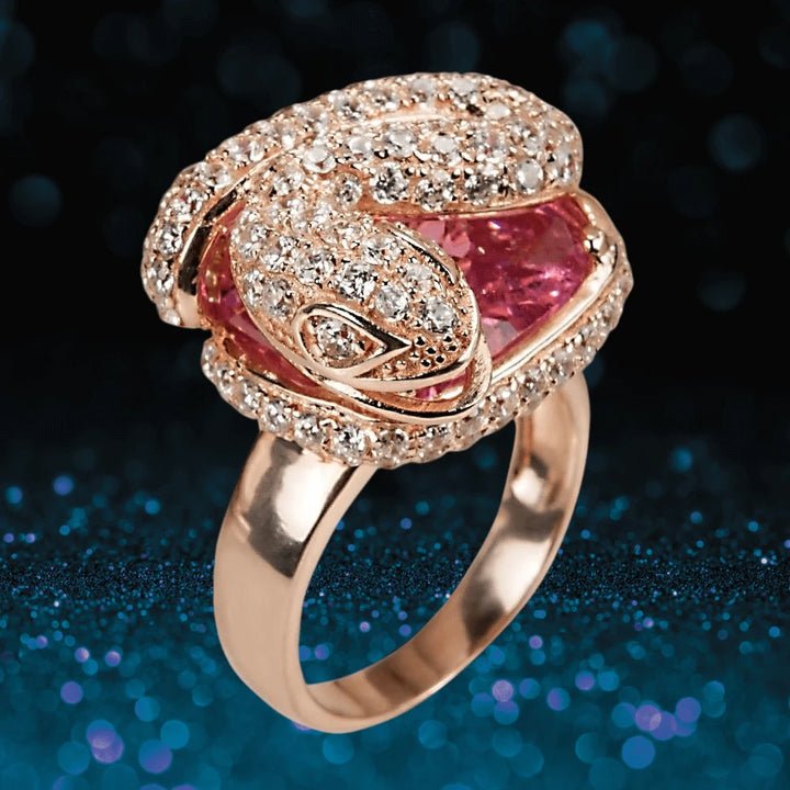 Snake Charmer Ring crafted from sterling silver with two-tone plating, featuring a detailed snake design adorned with sparkling stones and a pink gemstone centerpiece.