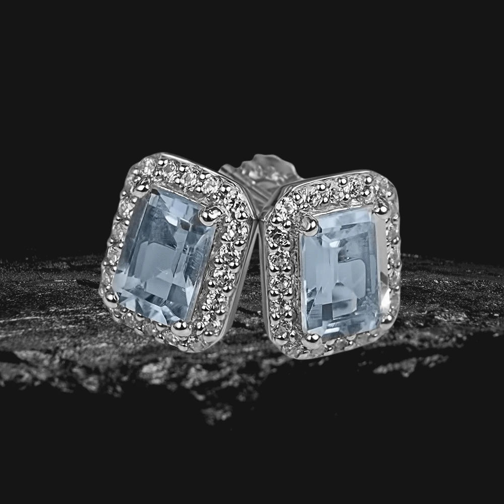 Destiny Topaz Earrings featuring rectangular light blue topaz stones set in sterling silver with rhodium plating and surrounded by small clear gemstones, designed for women.