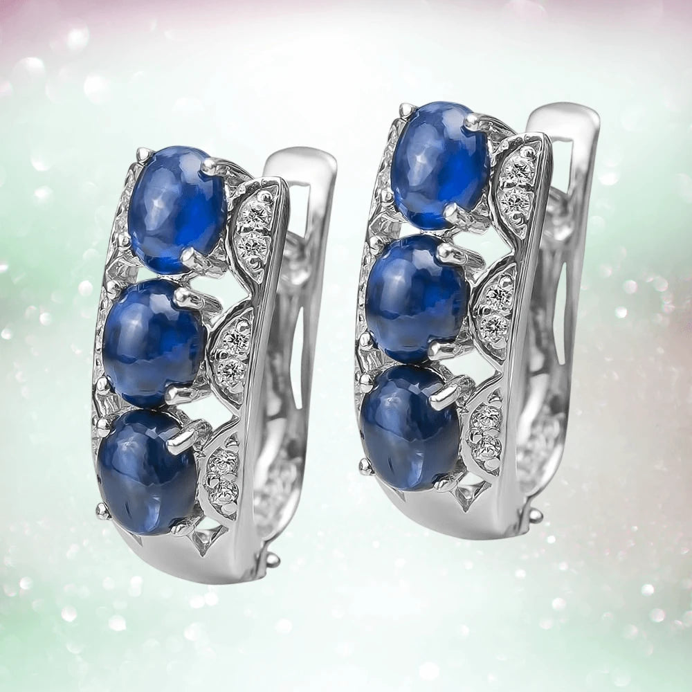 Berry Sapphire Earrings featuring three oval blue sapphire stones set in rhodium-plated sterling silver with sparkling accent stones, designed for women’s jewelry.