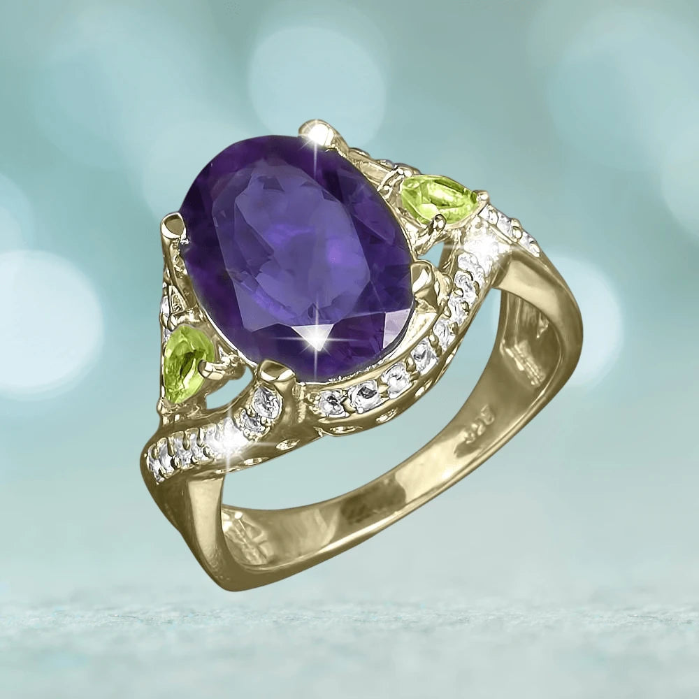 Sansiri Amethyst Ring features a large oval amethyst gemstone set in sterling silver with gold plating, accented by green peridot stones and small clear crystals for an elegant female jewelry piece.