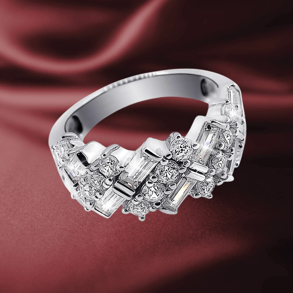 Sterling silver Ascot Ring for female with rhodium plating, featuring a geometric design adorned with sparkling clear gemstones on a smooth band against a silky red background.