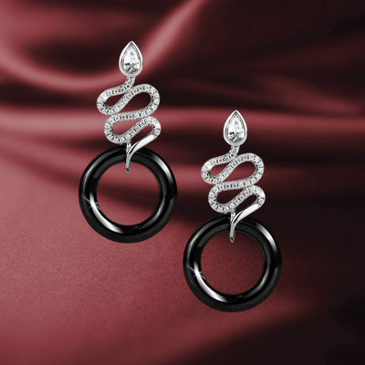 Ceramica Serpent Earrings featuring sterling silver with rhodium plating, designed for women, showcasing a serpent motif wrapped around a sleek black circular element on a satin background.