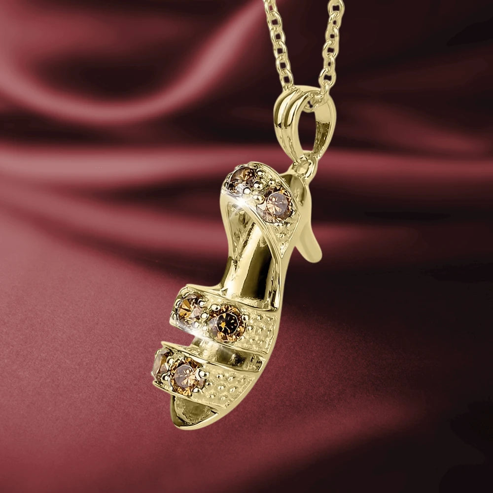 Close-up of a gold-plated sterling silver Kitten Heels Caramel Pendant adorned with caramel-colored gemstones, showcased on a delicate chain against a rich burgundy fabric background.