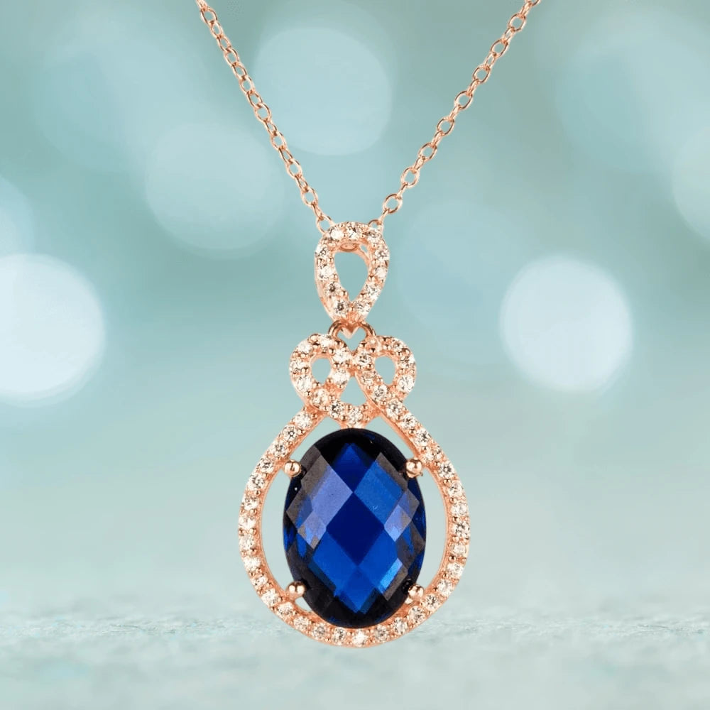 Rosa De Mer Pendant featuring a sterling silver setting plated in rose gold, showcasing a deep blue faceted gemstone surrounded by sparkling accents, elegant jewelry for women.