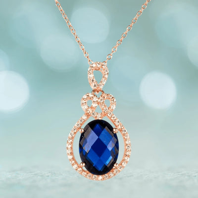Rosa De Mer Pendant featuring a sterling silver setting plated in rose gold, showcasing a deep blue faceted gemstone surrounded by sparkling accents, elegant jewelry for women.
