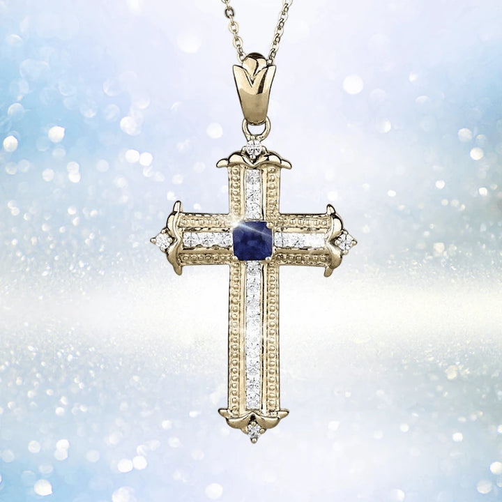 Sapphira Cross Pendant featuring a sterling silver cross plated in gold with a central blue sapphire gemstone, designed as a women's elegant jewelry necklace pendant.