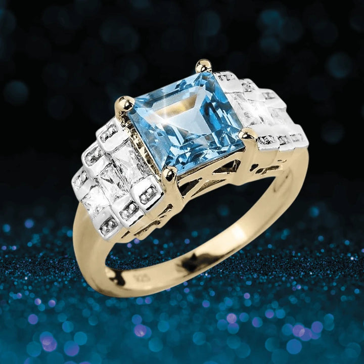 Oceana Blue Topaz Ring featuring a square blue topaz center stone set in gold-plated sterling silver with intricate detailing and clear accent stones, designed for women.
