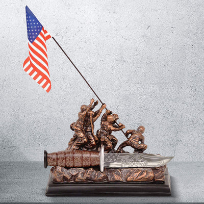 Bronze statue of soldiers raising an American flag with a knife on a gray background