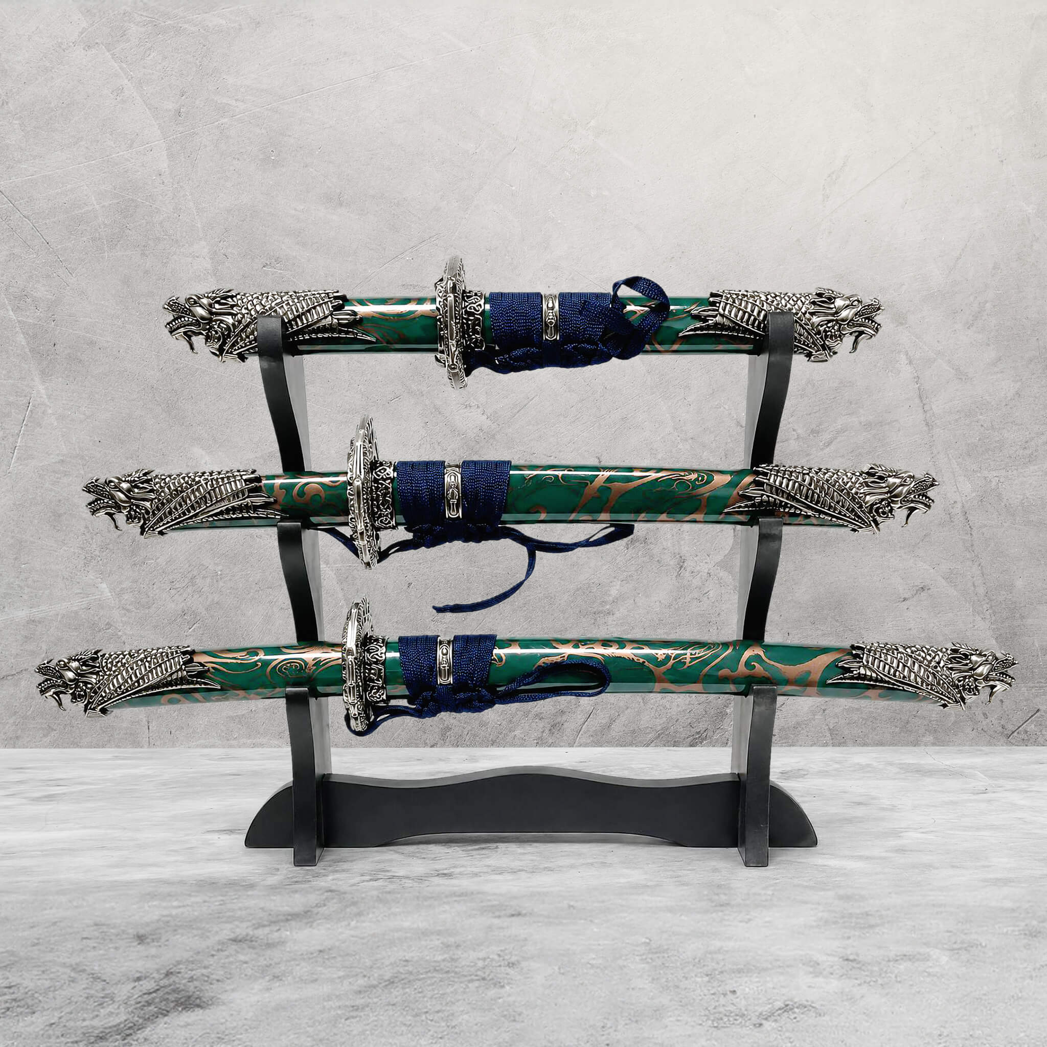 Jade Dragon Sword Set displayed on a black wooden stand featuring three intricately designed swords with green and gold patterned sheaths and detailed silver dragon-themed handles, Up To 75% Off Retail.