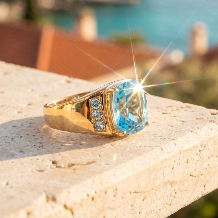A gleaming Aegean Blue Topaz Men's Ring with a large blue topaz stone set in polished gold, accented by smaller gemstones, displayed outdoors with sunlight sparkle, Up To 75% Off Retail.