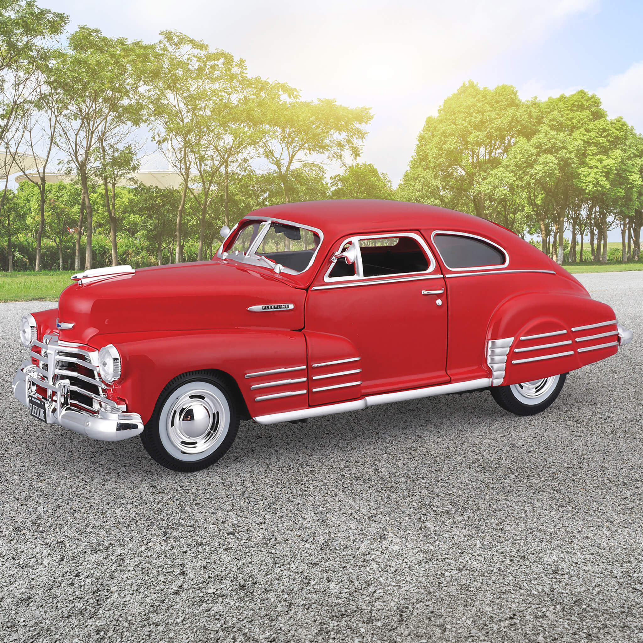 Red die cast model of the 1948 Chevrolet Fleetline Aerosedan displayed outdoors with trees in the background, Unisex collectible, Up To 75% Off Retail.