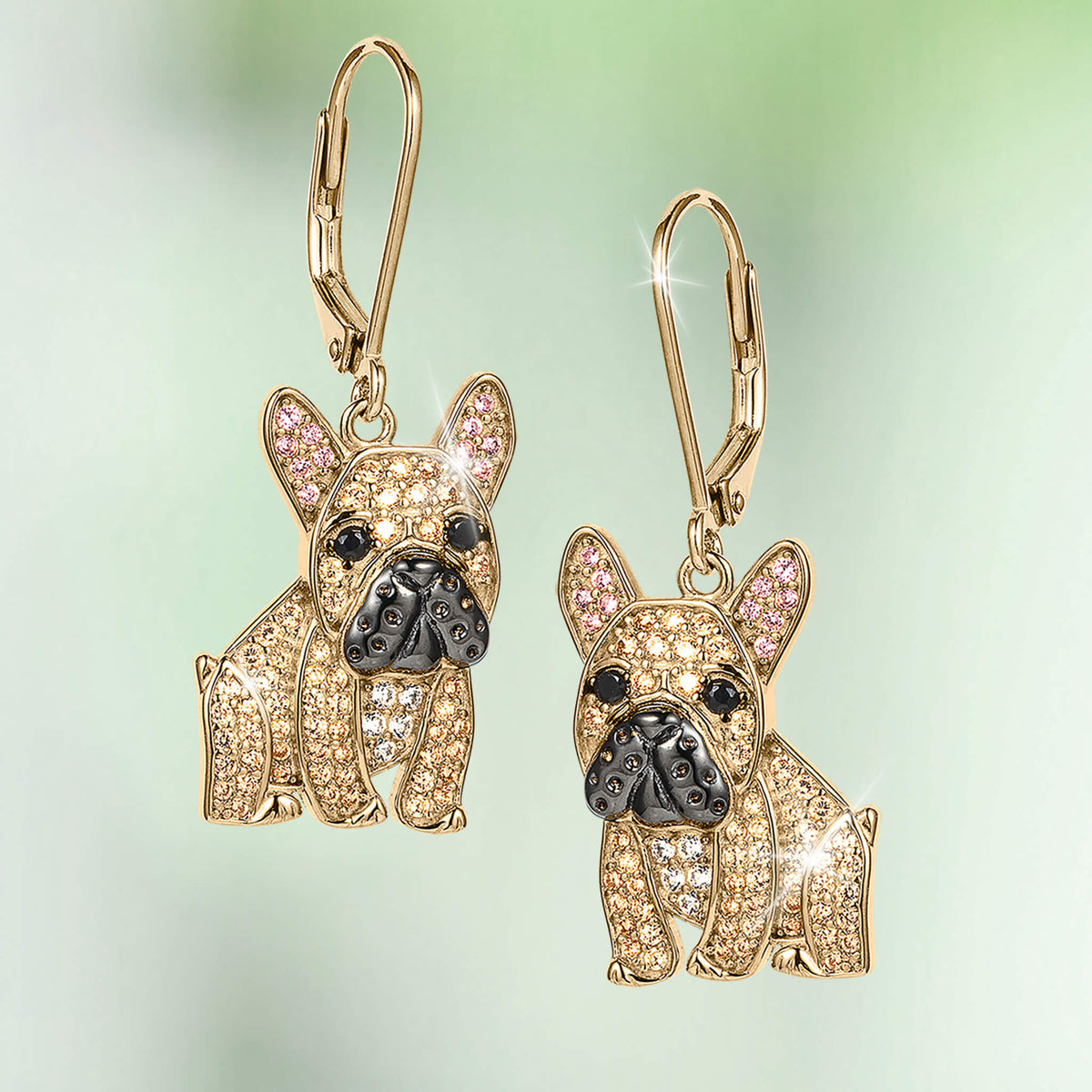 Forever Frenchie Earrings featuring gold French bulldog drop earrings with crystal details pink inner ears and black enamel noses on a soft green background