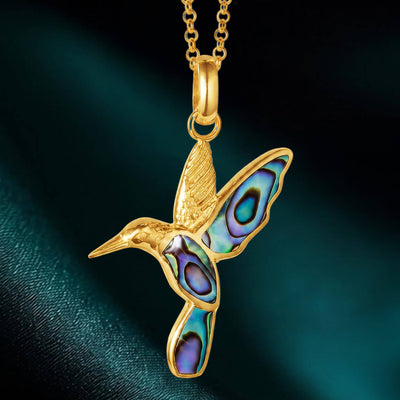 Golden Abalone Hummingbird Pendant featuring a gold-tone hummingbird with vibrant abalone shell inlays on its wings and tail, suspended on a delicate chain necklace.