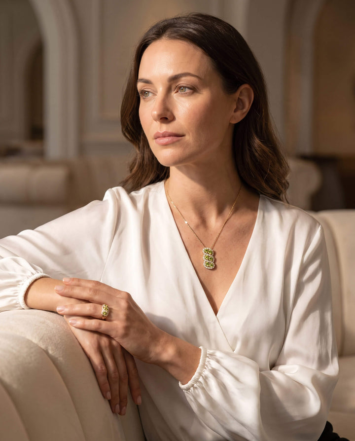 Woman wearing elegant green gemstone necklace and ring from the Elysian Peridot Collection, showcasing timeless jewelry style with a tagline Up To 75% Off Retail.