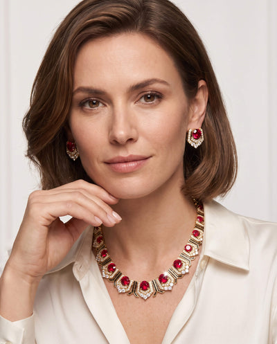 Elegant woman showcasing a red gemstone necklace and matching earrings from the Scarlet Heirloom Collection, featuring intricate gold accents, Up To 75% Off Retail.