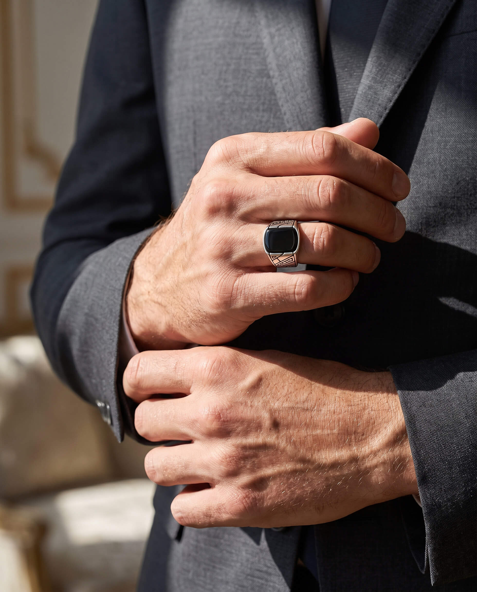Man dressed in a sharp suit wearing the Onyx Raven Men's Ring with a black stone and detailed silver band, showcasing elegance and style, Up To 75% Off Retail.