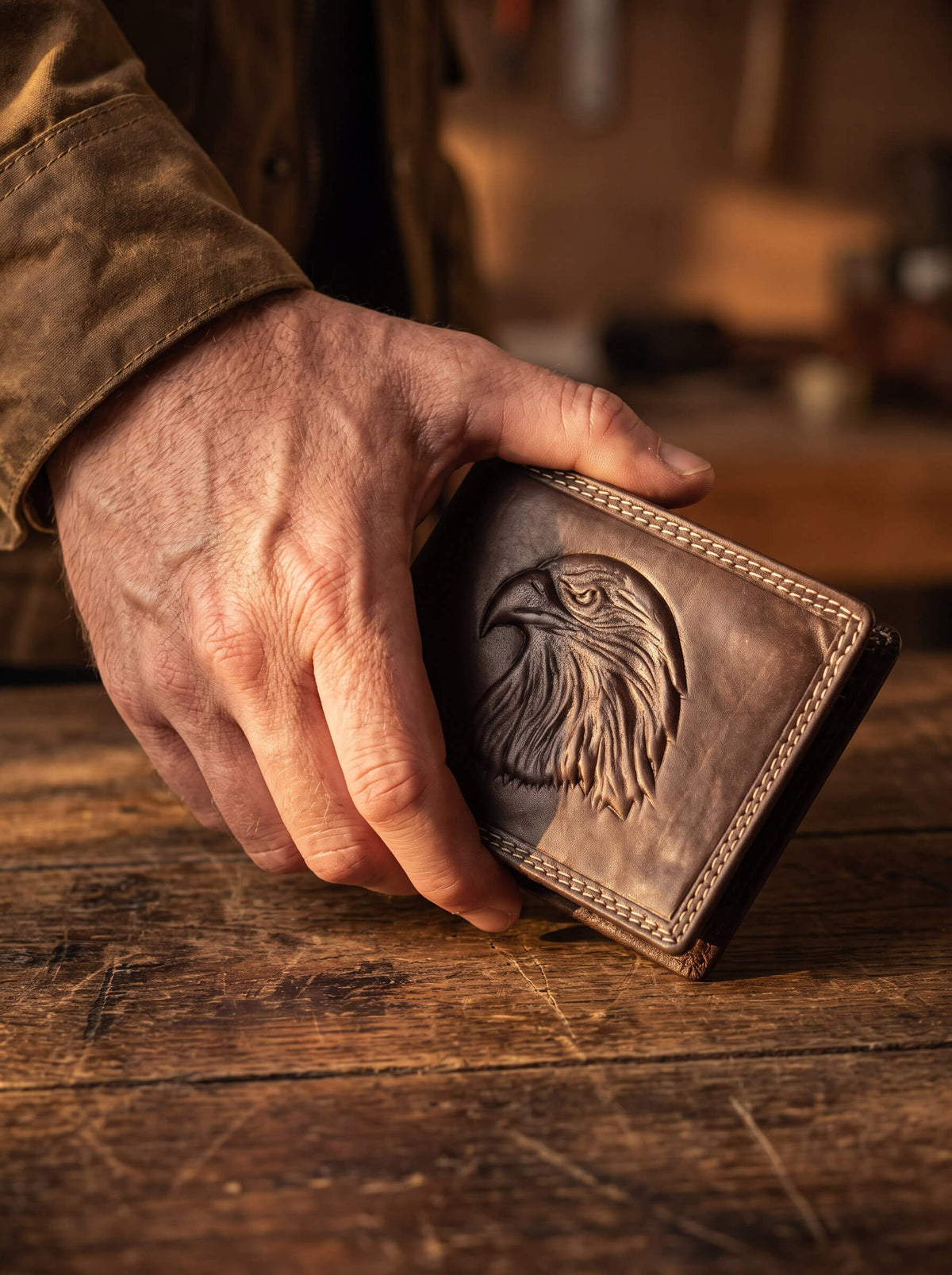 Eagle Predator Leather Wallet with embossed eagle artwork and stitched leather detailing held over a rustic wooden table Up To 75% Off Retail