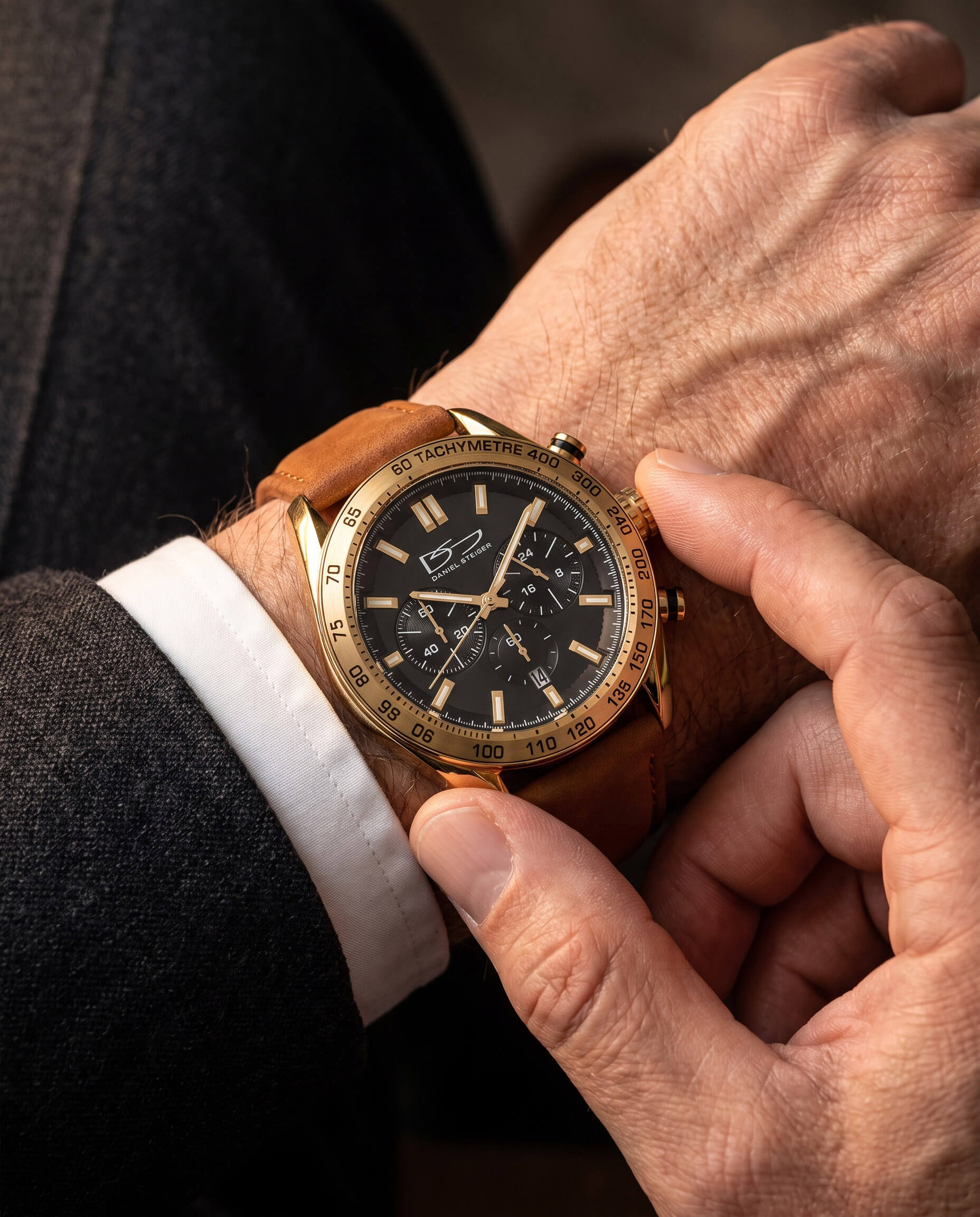 A close-up of a person adjusting the gold-tone Citadel Chrono Men's Watch with a black dial and brown leather strap, showcasing its elegant design and chronograph features, Up To 75% Off Retail.
