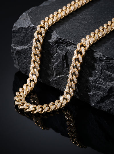 Magnus Necklace featuring a polished gold tone Cuban link design with sparkling accents styled on black stone for a bold luxurious jewelry presentation