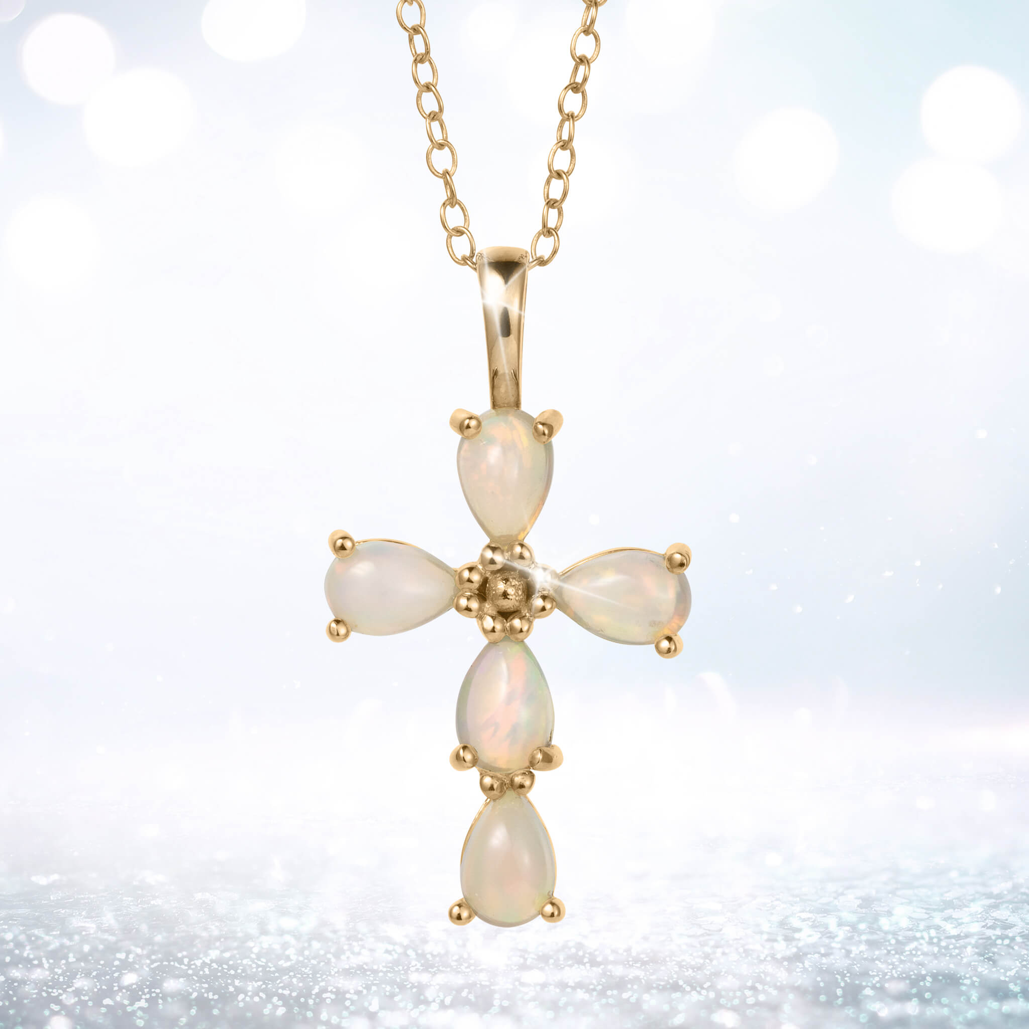 Ayana Opal Cross Pendant with luminous opal stones in a cross design on a gold tone chain against a softly glowing background
