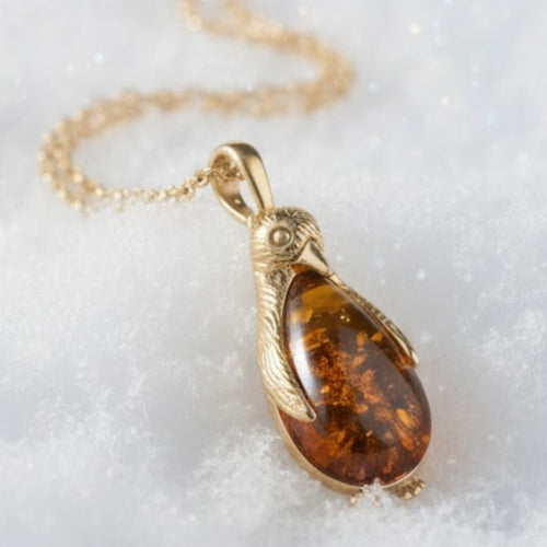 Gold necklace with a amber pendant on a white background. Penguin Baltic Amber Pendant