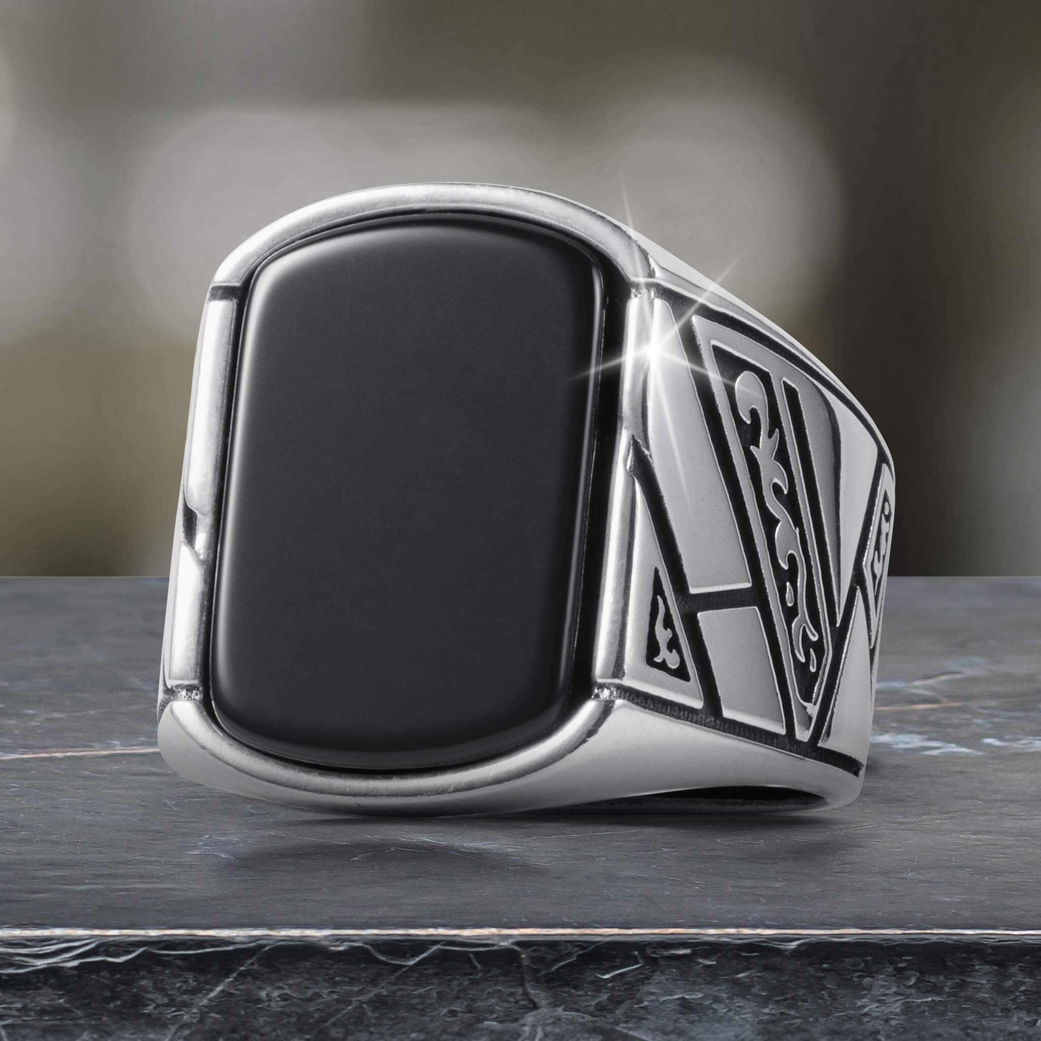 Close-up of a sleek Onyx Raven Men's Ring featuring a bold black onyx center stone and intricate silver detailing, available Up To 75% Off Retail.