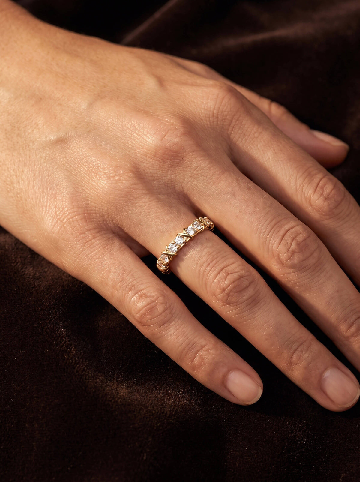 Golden Kiss Ladies Ring with a sparkling gold band and clear stones worn on a hand against dark satin Up To 75% Off Retail