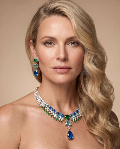 Elegant female model wearing gold-plated Midnight Riviera Earrings paired with a matching gemstone necklace, showcasing luxurious jewelry with Up To 75% Off Retail.