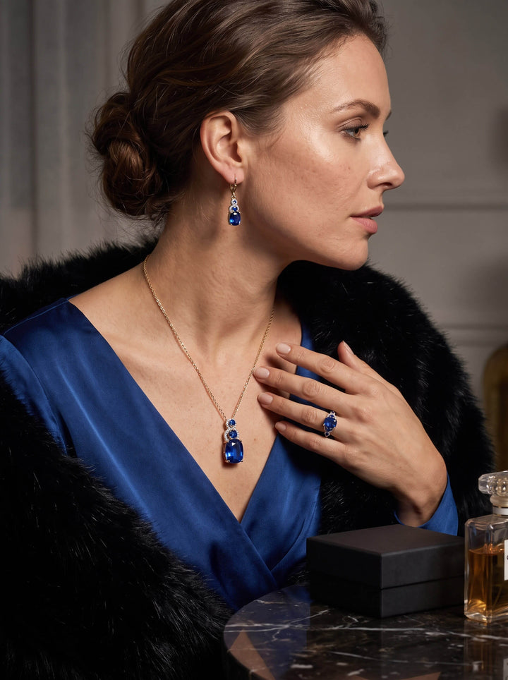 Elara Sapphire Collection featuring a woman wearing elegant blue sapphire earrings necklace and ring with a luxurious black fur wrap. Up To 75% Off Retail