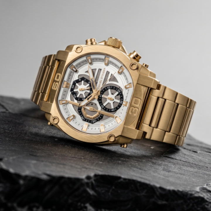 Close-up of a luxurious Titan Gold Men's Watch with a gold metal bracelet and detailed white and black chronograph dial, showcased on a dark textured surface with Up To 75% Off Retail. Daniel Steiger Titan Gold Men's Watch