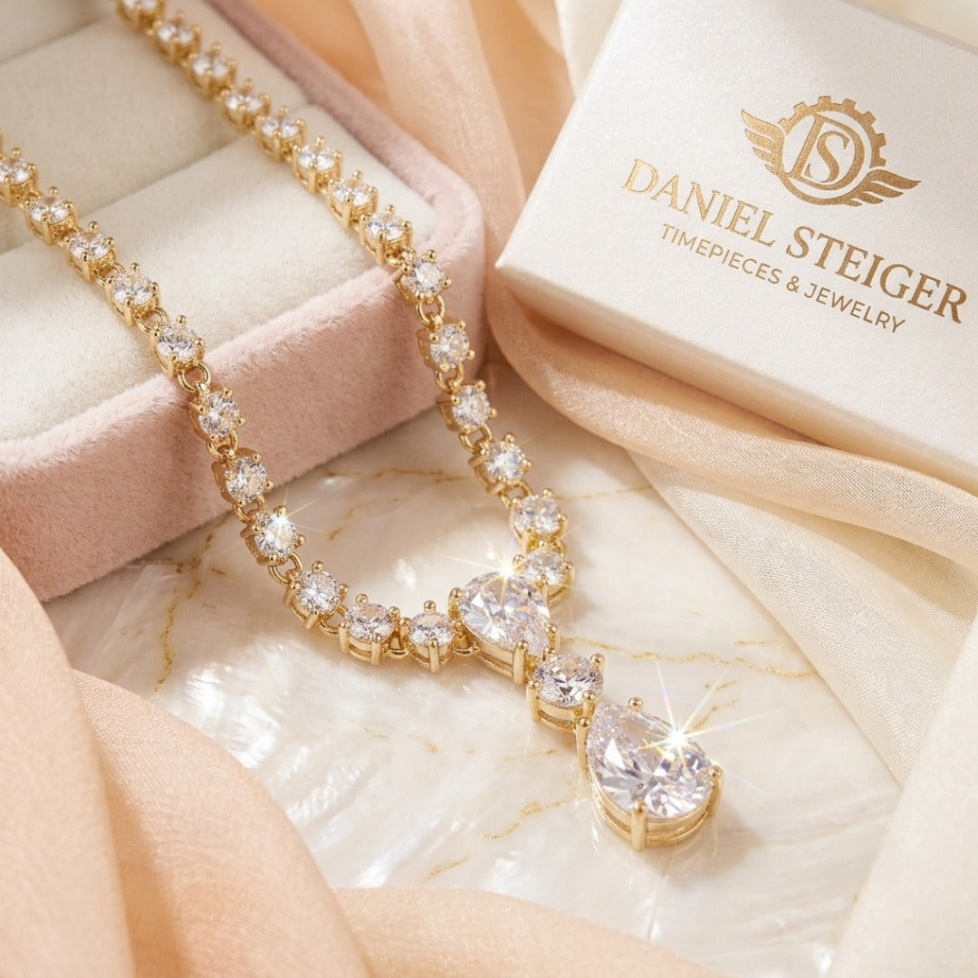 Gold necklace with clear stones on a Daniel Steiger branded box and fabric background