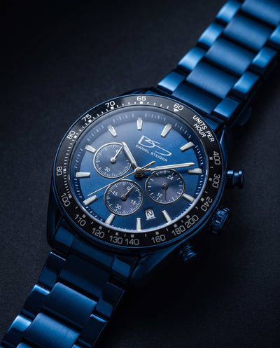 Close-up of a sleek Midnight Velocity Men's Watch with a blue metal bracelet, detailed chronograph dials, and tachymeter bezel, showcasing precision and stylish design.
