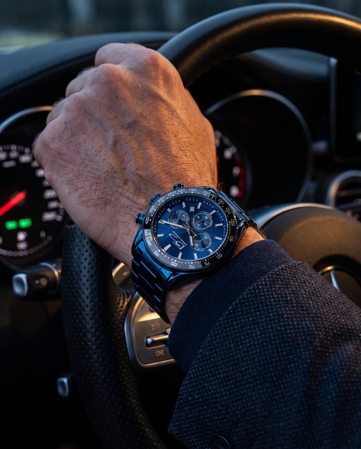 Close-up of a wrist wearing the Midnight Velocity Men's Watch with a dark metallic band, detailed chronograph dial, held on a steering wheel, showcasing style and precision with Up To 75% Off Retail.