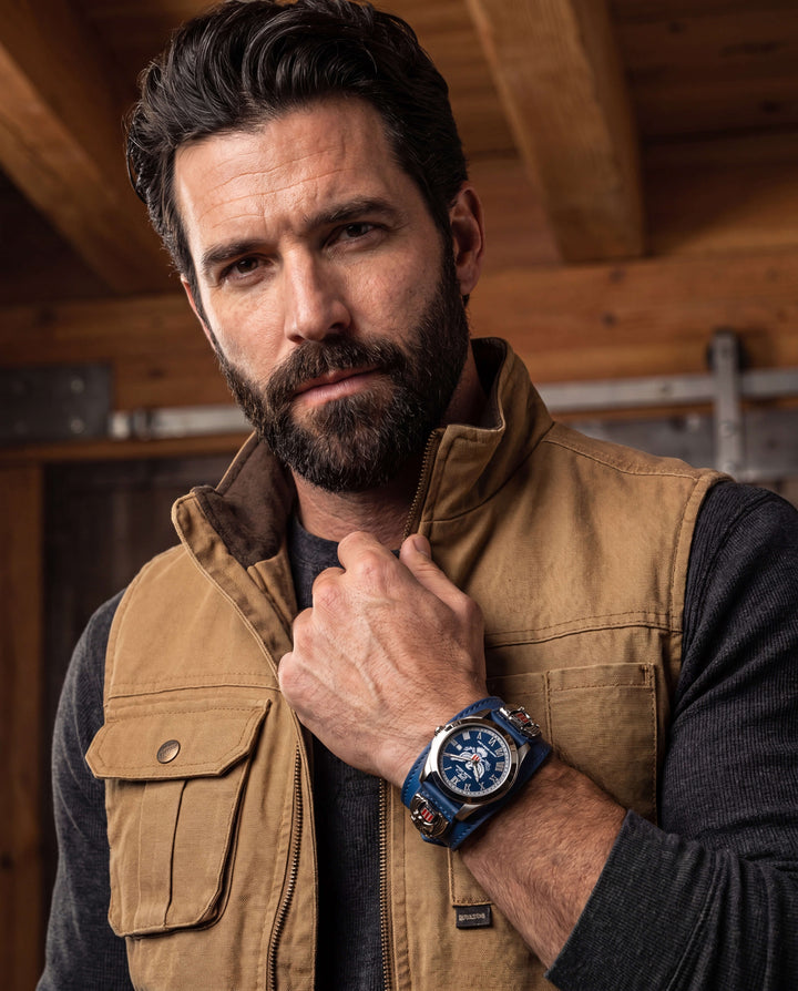 Man wearing a brown vest and black shirt showcasing the Patriot 250 Years Blue Limited Edition Watch with a blue dial and stainless steel case, Up To 75% Off Retail.
