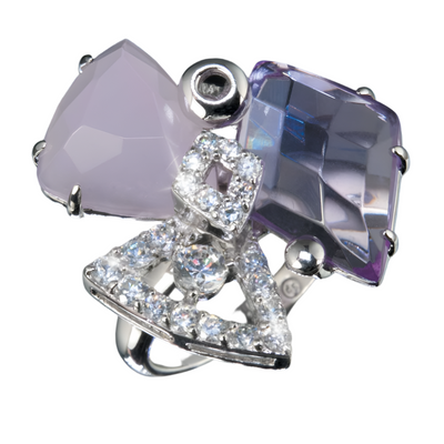 Close-up of a Pink Modernista Ring featuring two large faceted stones in soft pink and violet hues, accented with a silver geometric design adorned with sparkling clear crystals, designed for female jewelry enthusiasts.