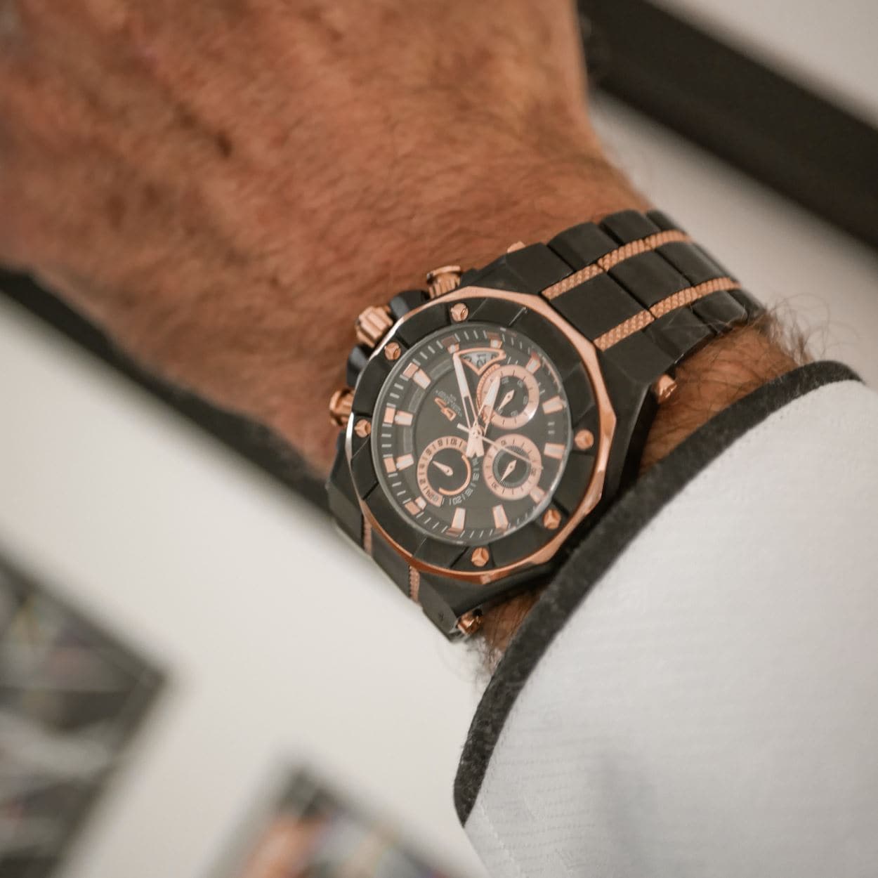 Phantom Black Men's Watch featuring a two-tone stainless steel band with black and rose gold accents, worn on the wrist of a person dressed in a white suit jacket.