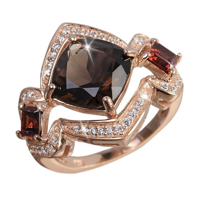 Cocoa Santana Ring featuring a sterling silver band plated in rose gold, adorned with a large dark central gemstone and two smaller red gemstones surrounded by sparkling accents.