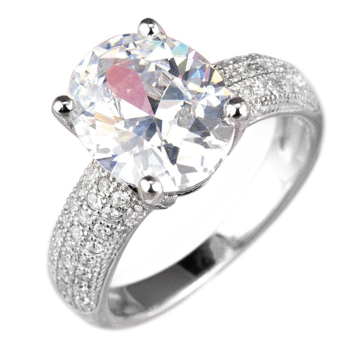 Caravella Rhodium Ring featuring a sterling silver band with rhodium plating, adorned with a large sparkling oval-cut center stone and smaller pavé-set stones on the band.